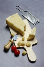 A piece of Parmesan cheese and chopped pieces of cheese on a wooden board