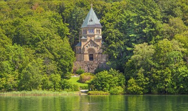 Votive chapel Memorial Chapel of St Ludwig on the lakeshore with wooden cross in the lake, the