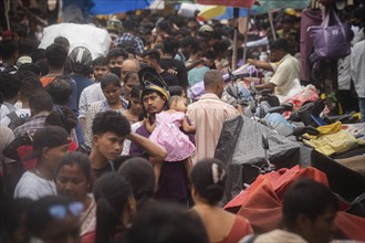 A person with his child in the crowd of people to shop at a street market ahead of Durga Puja