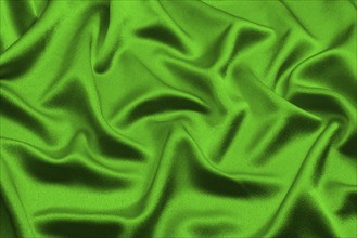 Green silk lies in soft, irregular folds