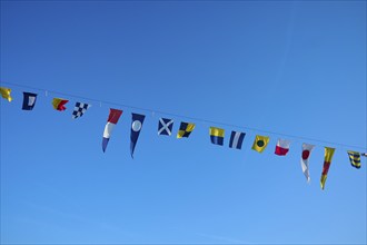 Several colourful flags hanging on a line in front of a clear blue sky, Hamburg, Germany, Europe