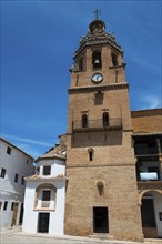 Historic brick church tower with clock in front of a clear blue sky in a sunny old town, church,