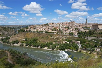 View of a historic city on a hill with a river flowing by and green landscape, Toledo, River Tagus,