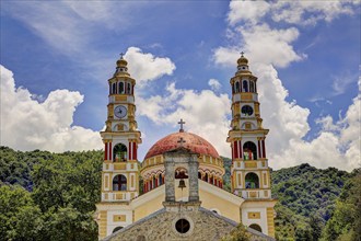 Magnificent church with two towers in front of a wooded mountain landscape and a cloudy sky, Church