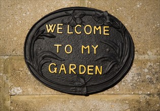 Close up of a 'Welcome to my Garden' sign fixed on wall of a house