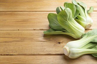 Fresh green bok choy or pac choi chinese cabbage on a brown wooden background. Side view, close up,