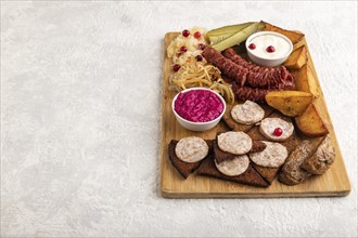 Set of snacks: sausages, toast, sauerkraut, marinated onion and cucumber, baked potato on a cutting