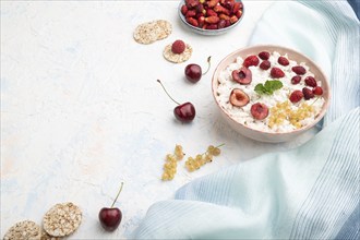 Rice flakes porridge with milk and strawberry in ceramic bowl on white concrete background and blue