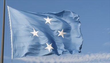 The flag of Micronesia, Pacific Islands, fluttering in the wind, isolated against a blue sky