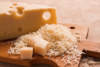 Grated cheese, Maasdam, on a cutting board, grater and cheese knife, close-up, no people