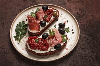 Sandwiches with cheese and prosciutto, dried tomatoes and olives, breakfast on a plate