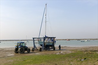 Tractor launching boat in cradle, River Blackwater estuary, West Mersea, Mersea Island, Essex,