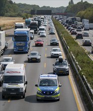 Police patrol car with flashing blue lights and siren working its way through a traffic jam on the