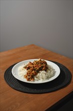 Homemade chicken stew with corn, peas, tomato, bell pepper and rice on wooden kitchen table