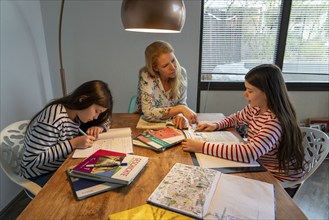 Homeschooling, during the lockdown in January 2021, mother helps her two daughters, at home,