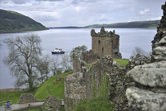 Cruise boat on Loch Ness in front of the ruins of Urquhart Castle near Drumnadrochit, Scotland, UK