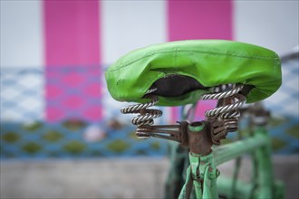 Green bicycle saddle, green bicycle in front of white-pink coloured temple outer wall, Tamil Nadu,