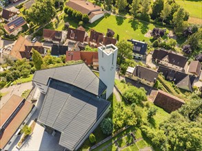 A village with a striking church and a tower, nestled in a green, hilly landscape, Gundringen,