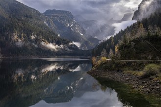 The Vordere Gosausee in autumn. In the background, the Dachstein mountain range in clouds. Cloudy