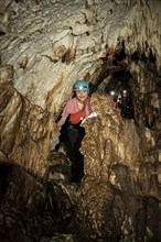 Young woman with helmet and headlamp, tourist between stalactites and stalagmites in a stalactite