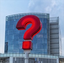 Red question mark on the streets of Singapore with a modern building in the background