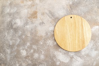 Empty round wooden cutting board on brown concrete background. Top view, copy space, flat lay