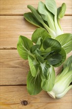 Fresh green bok choy or pac choi chinese cabbage on a brown wooden background. Top view, close up,