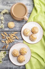 Almond cookies and a cup of coffee on a gray wooden background and green linen textile. Top view,