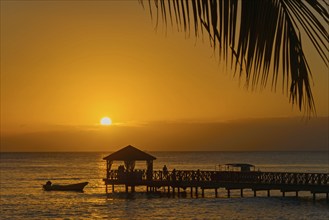 Atmospheric sunset with a boat near a busy jetty, Dominicus beach, Bayahibe, Dominican Republic,