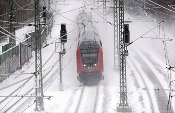 A Deutsche Bahn regional train runs over snow-covered railway tracks and stirs up snow, Berlin,