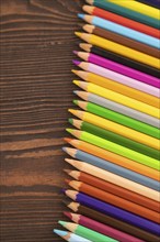 Set of watercolor pencils on brown wooden background. Top view, flat lay, close up