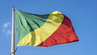 The flag of Congo flutters in the wind, isolated against a blue sky