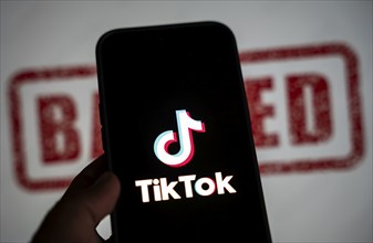 In this photo illustration, logo of Tiktok is displayed on mobile phone screen next to ban sign, in