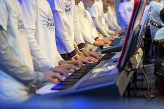 Young people, children play on many keyboards, simultaneously, electronic clarinet, at a concert