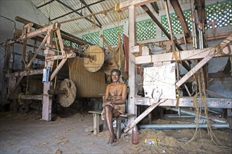 Indian worker, 68 years old, sitting in the weaving mill of the Labourers Coir Mats and Mattings