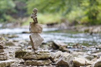 Stacked stones on the riverbank in balance, surrounded by green nature