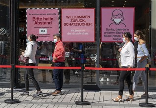 Queue in front of a clothing shop, Corona protective measures, posters for compulsory masks,