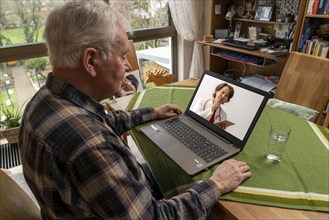 Symbolic image of telemedicine, elderly patient speaking to a doctor in a video conference from