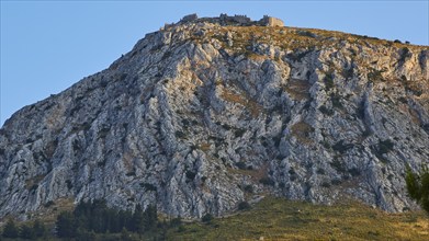 The golden hour illuminates a mountain with an ancient castle at the top, Archaic Castle,