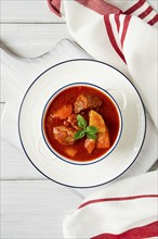 Potatoes stewed with meat, in tomato sauce, with spices and herbs, no people, on a white table