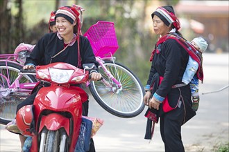 Vietnamese woman in traditional traditional costume from the Dao minority transport a pink bicycle