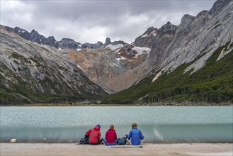 Hikers sitting on the shore of the glacial lake Laguna Esmeralda, Tierra del Fuego Island,