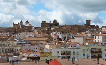 Panoramic view of a historic town with houses and fortifications under a cloudy sky, Cáceres,