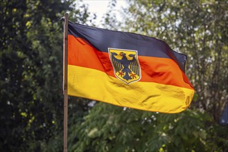 German flag with federal eagle fluttering in the wind, Münsingen, Baden-Württemberg, Germany,