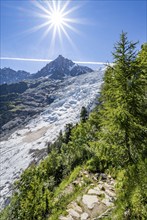 View of glacier Glacier des Bossons with sun star, behind summit of Aiguille du Midi, Chamonix,