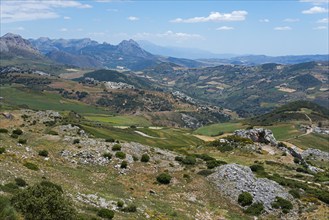 Extensive mountain landscape with valleys and green areas under a cloudy sky, view from the nature