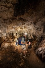 Young man with helmet and headlamp, tourist between stalactites and stalagmites in a stalactite