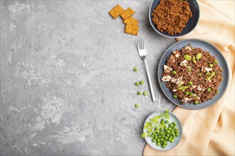 Quinoa porridge with green pea and chicken on ceramic plate on a gray concrete background and