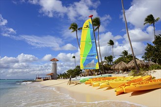 Colourful sailboat on tropical beach with lighthouse and kayaks in the sand, lighthouse, bar of