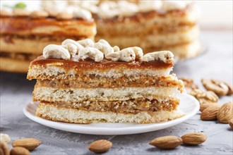 Piece of homemade cake with caramel cream and nuts on a gray concrete background. side view, close